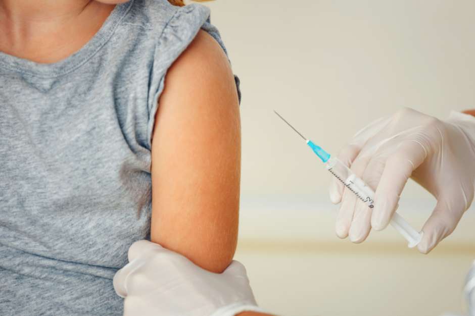 Doctor vaccinating small redhead girl.