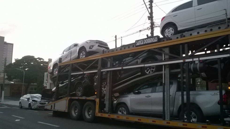 Carro fica destruído após cair de caminhão cegonha