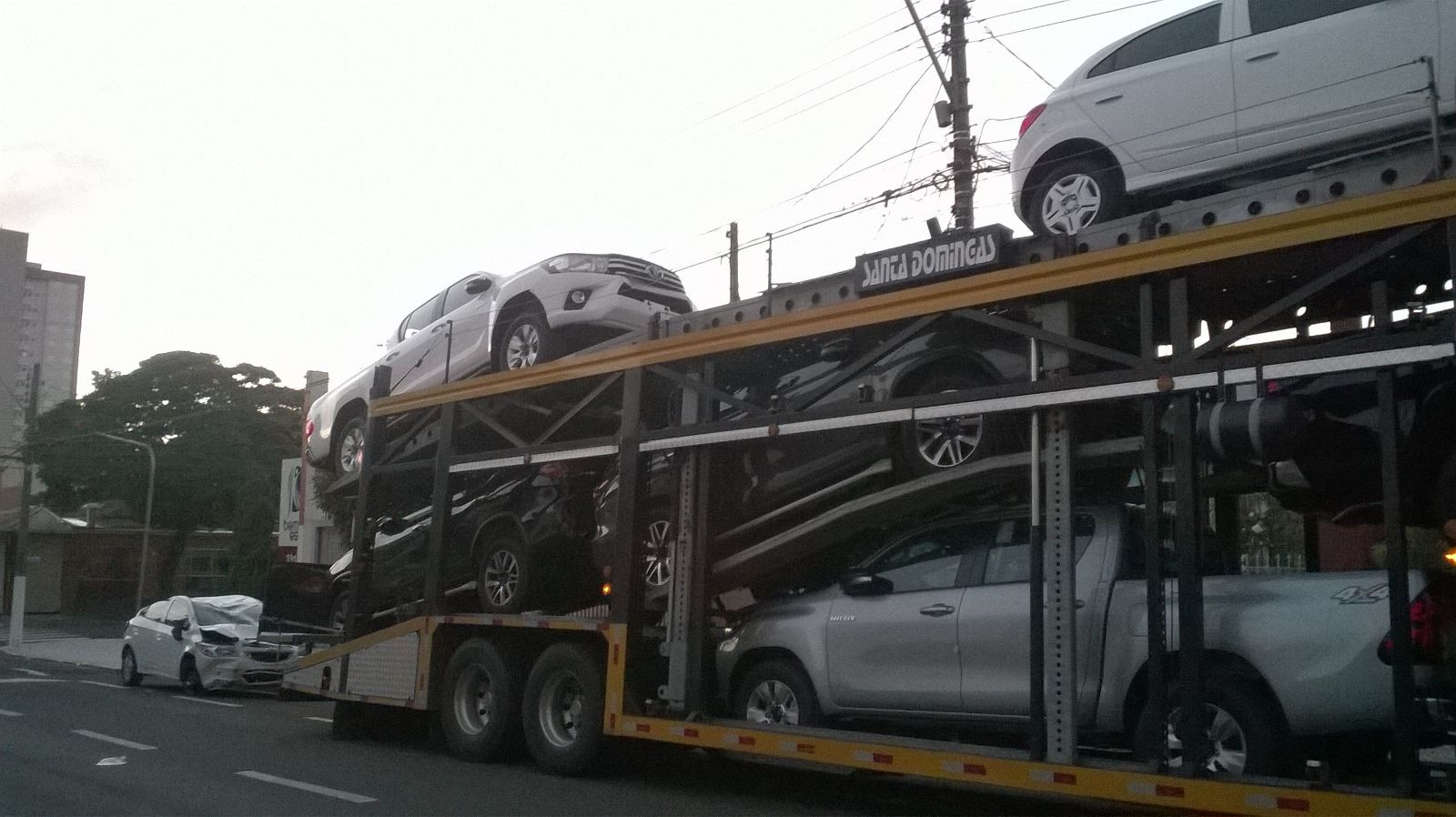 Carro fica destruído após cair de caminhão-cegonha que entalou em