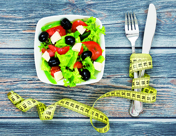 42356383 - fitness salad and measuring tape on rustic wooden table.